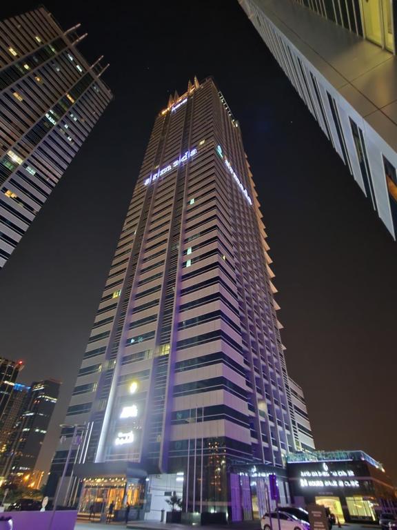 迪拜Armada Avenue Hotel - formerly Armada BlueBay Hotel的一座高大的建筑,上面有灯,晚上