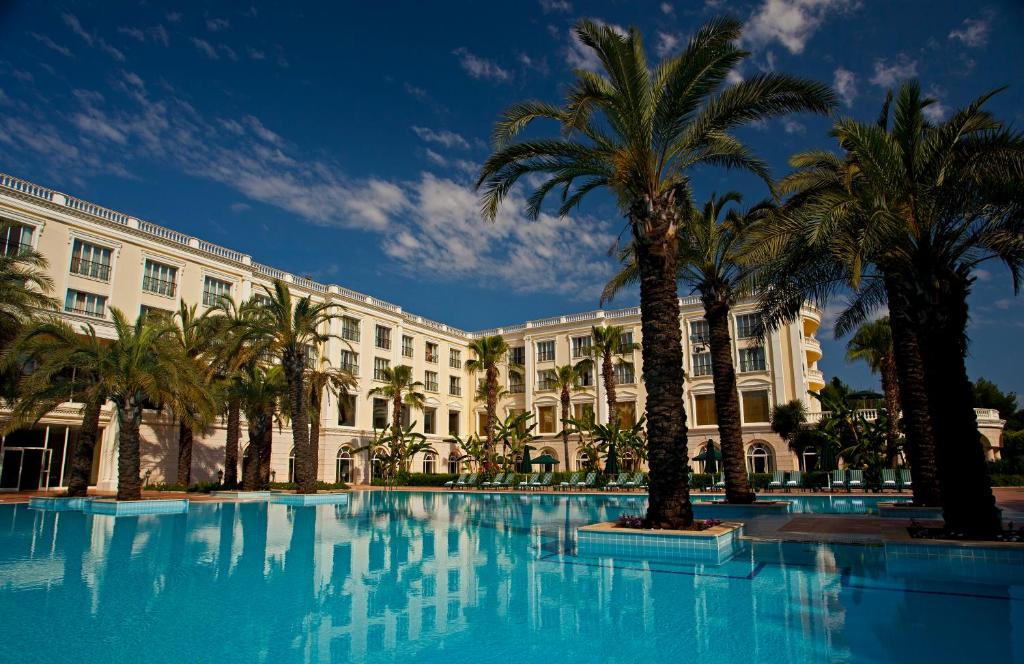 安塔利亚IC机场酒店的一座大型游泳池,在一座建筑前种有棕榈树
