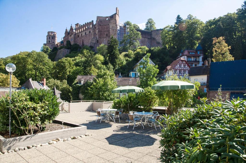 海德堡施洛斯酒店的庭院配有桌椅,后面是城堡