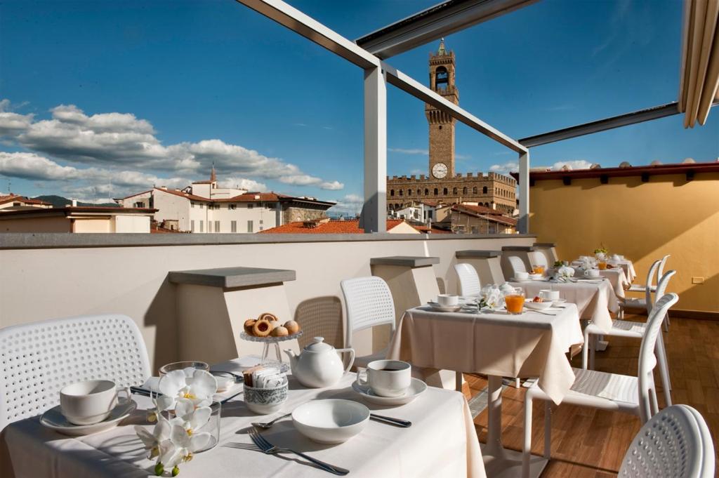 佛罗伦萨德拉斯吉诺日艾酒店的一间设有白色桌椅和钟楼的餐厅