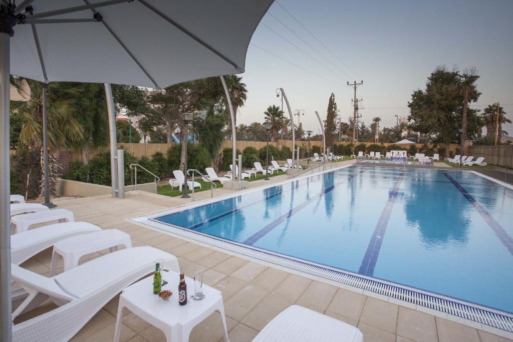 耶鲁姆Desert Iris Hotel的一个带白色椅子和遮阳伞的游泳池