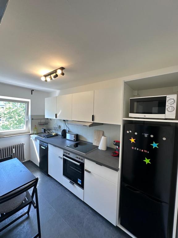 斯图加特Double Bed Apartment - Near Marienplatz的厨房配有黑冰箱和白色橱柜。
