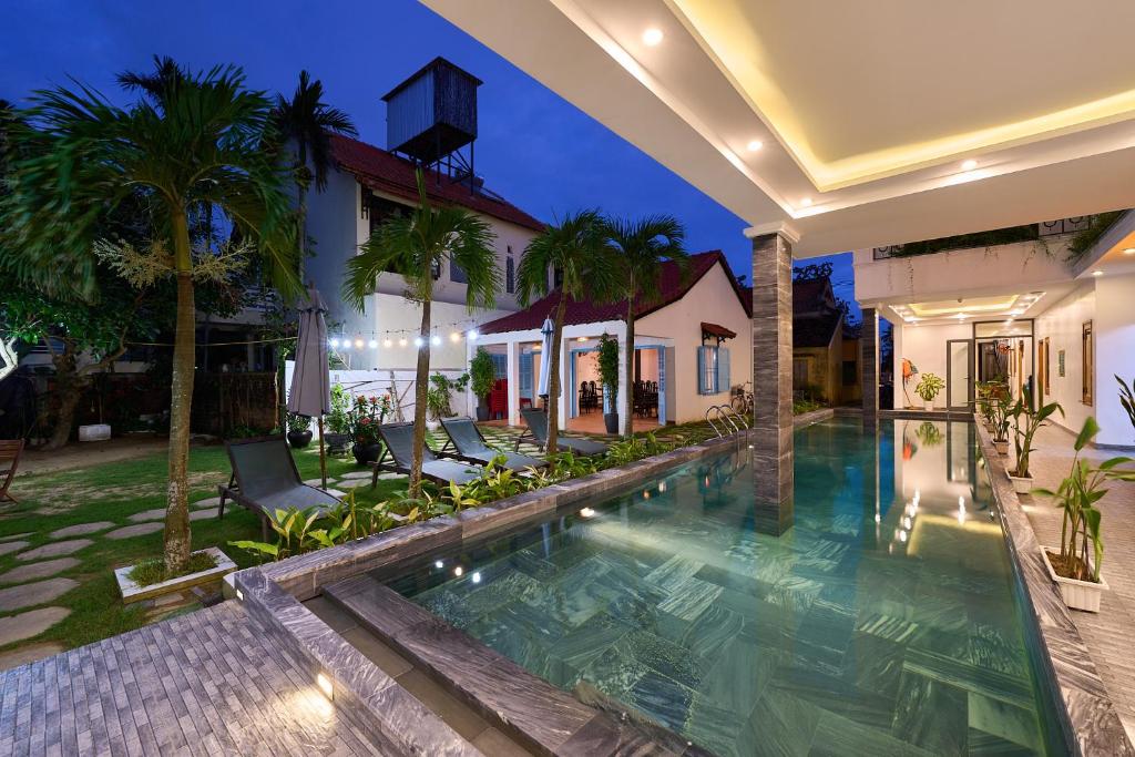 会安Hoi An Legend Charm Boutique Hotel的一张别墅的图片,晚上有一座游泳池