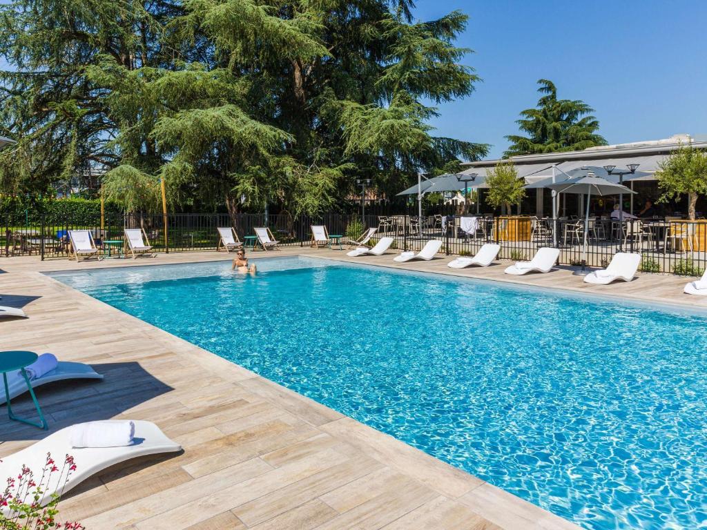 莱斯卡尔波城比利牛斯诺富特酒店的度假酒店内带躺椅的游泳池
