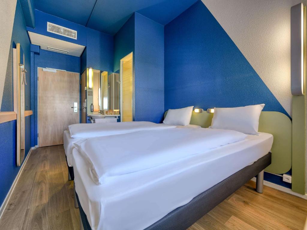 卢塞恩卢塞恩城宜必思快捷酒店的蓝色墙壁的房间里一张大白色的床