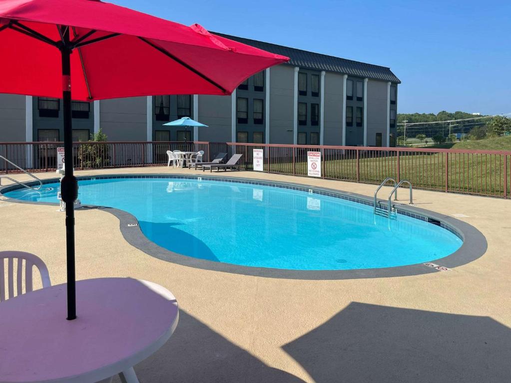 列克星敦Quality Inn & Suites的一个带桌子和红伞的游泳池