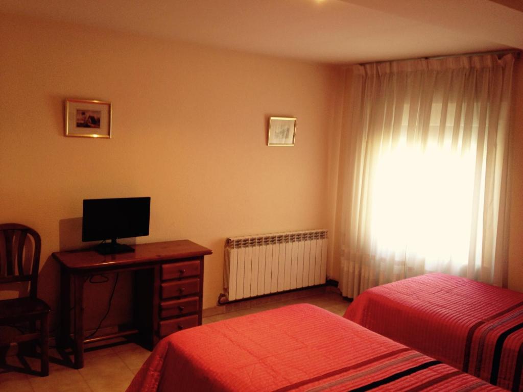 梅迪纳塞利Hostal Nicolás的一间卧室设有两张床、一台电视和一扇窗户。