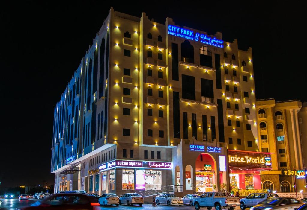 马斯喀特City Park Hotel Apartments的一座大型建筑,前面有汽车停放