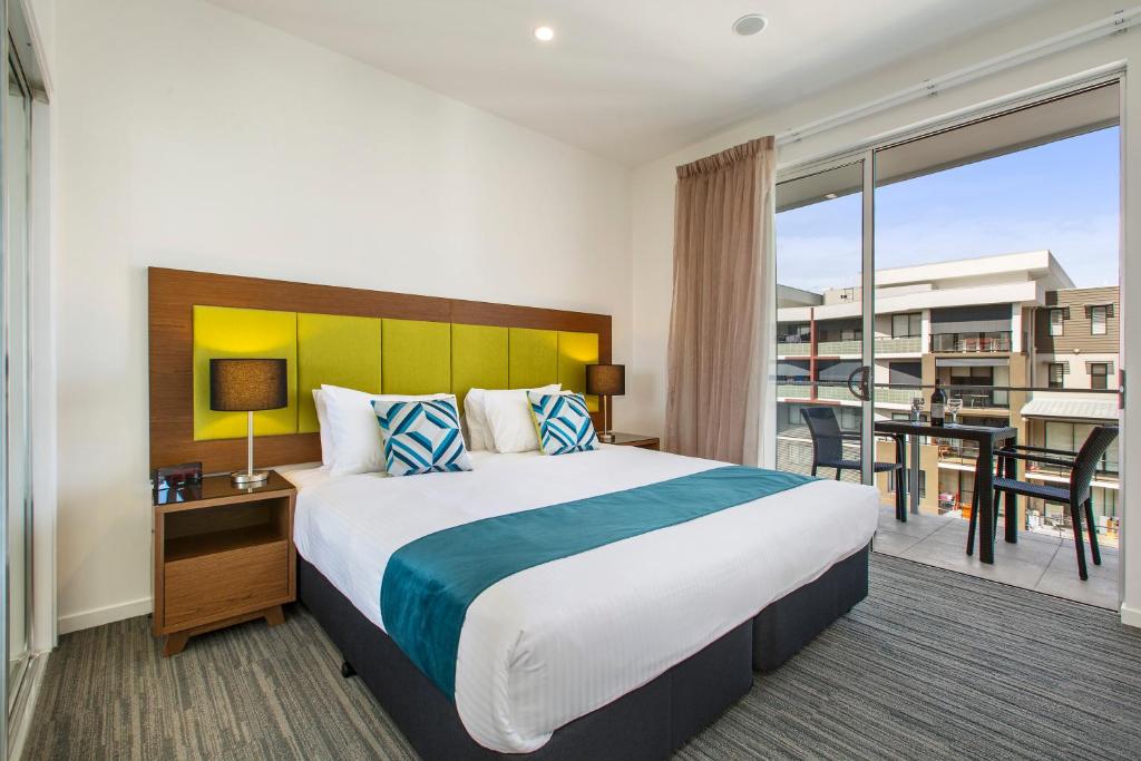 布里斯班奎斯特彻姆赛德操场公寓的酒店客房设有一张大床和一个阳台。