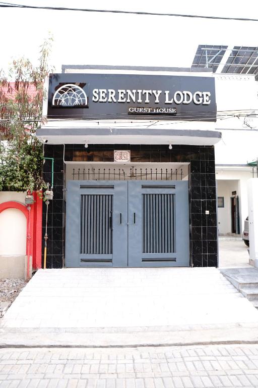 卡拉尔哥特Serenity Lodge Guest House的一座建筑,设有两个车库门和一个可读的标志