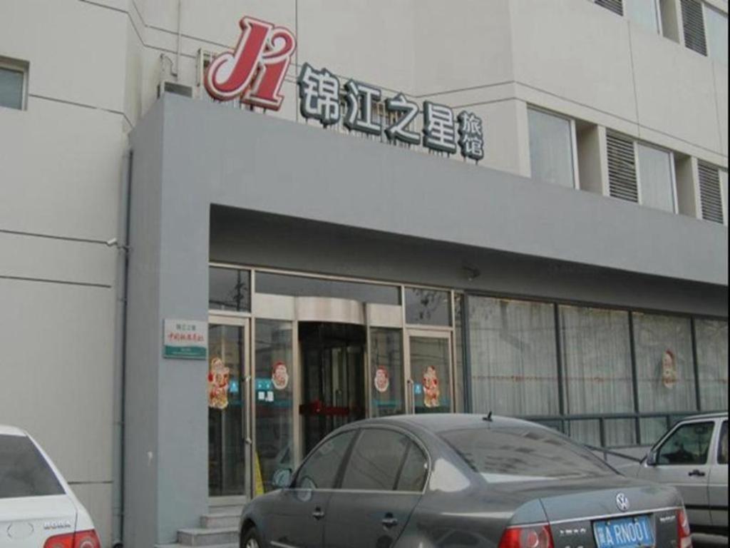 天津Jinjiang Inn Tianjin Zhongshan Road的前面有汽车停放的建筑