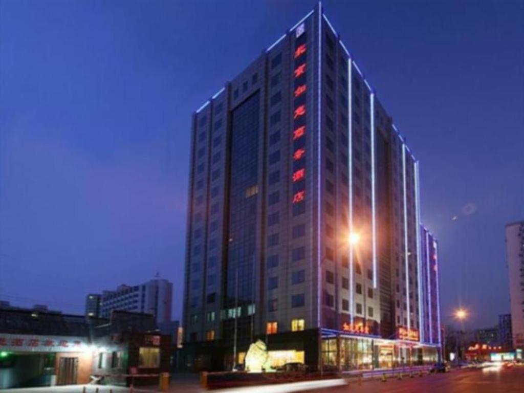 北京Beijing Ruyi Business Hotel的一座高大的建筑,晚上有红灯