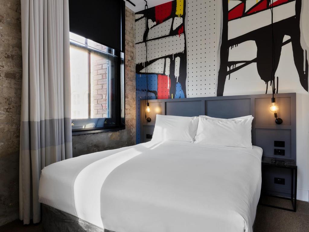 悉尼Hotel Woolstore 1888, Sydney - Handwritten Collection的卧室设有一张白色大床和一扇窗户。
