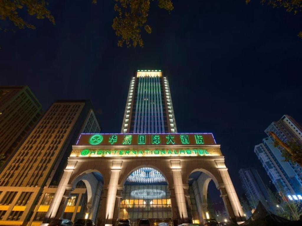 重庆Chongqing Huachen International Hotel的一座在晚上有绿灯的大建筑