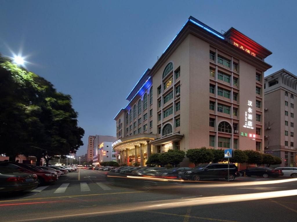 ShenzhenShenzhen Hanyong Hotel Fuyong Branch的城市街道上的一座建筑物,有车辆停放