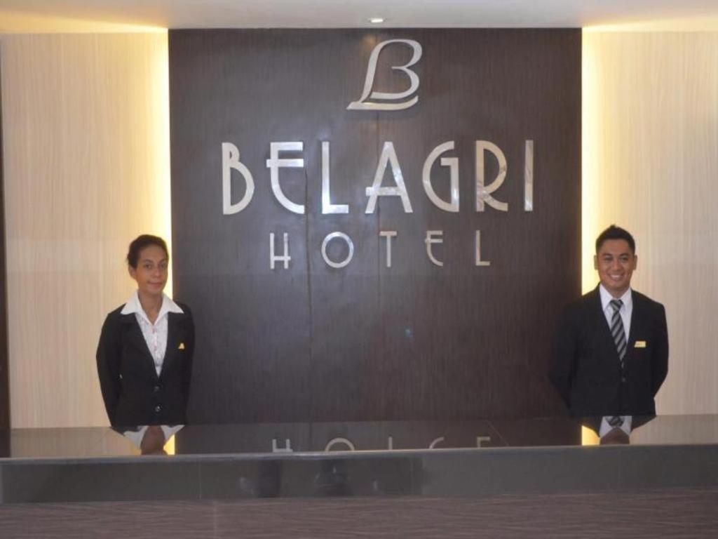 索龙Belagri Hotel And Restaurant的两个人站在旅馆前