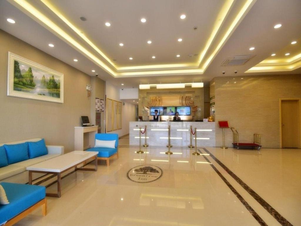 上海GreenTree Inn Shanghai National Convention and Exhibition Center Huaxiang Road的一间带蓝色家具的客厅和一间厨房