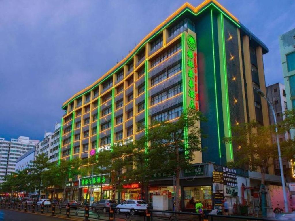 海口GreenTree Inn Haikou City Wuzhishan Road的一座大型建筑,旁边设有 ⁇ 虹灯标志