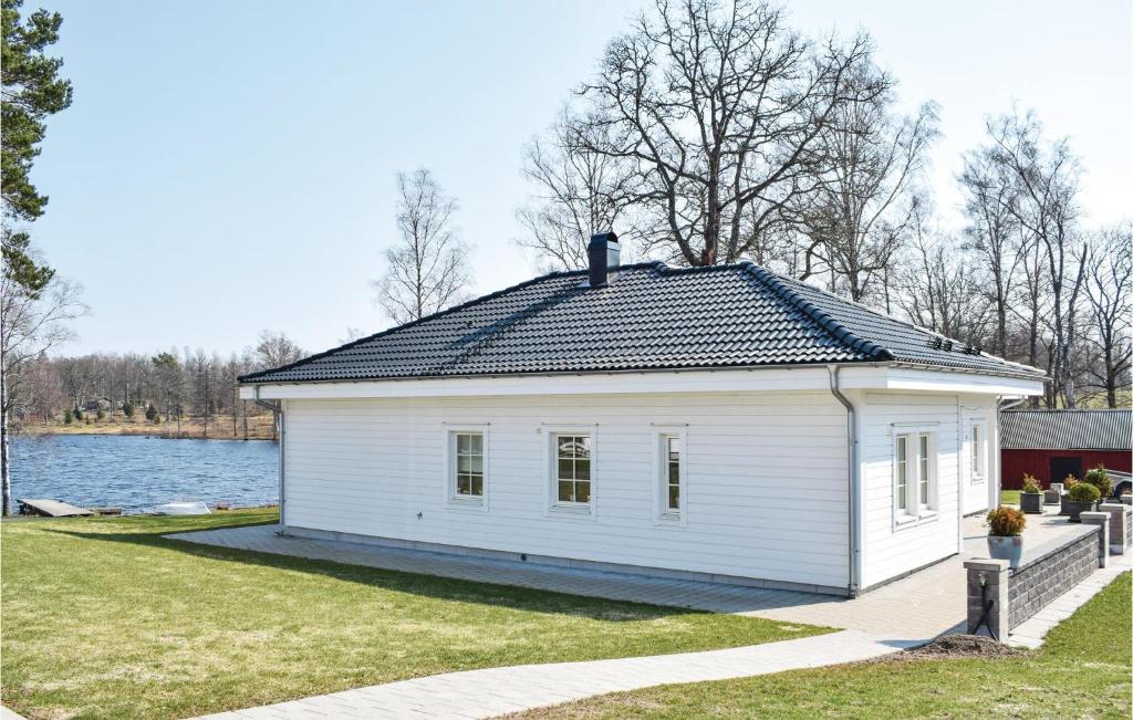 ÅsedaGorgeous Home In Åseda With Wifi的湖畔的白色房子,有黑色的屋顶