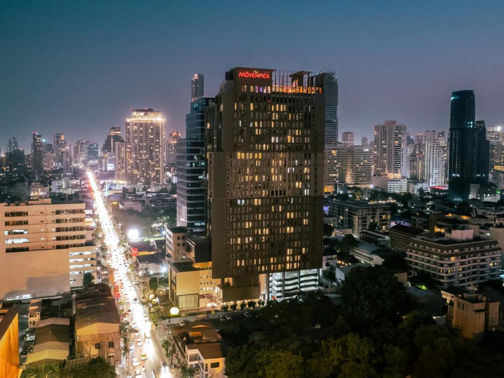 曼谷Mövenpick Residences Ekkamai Bangkok的城市天际线,夜晚有高楼