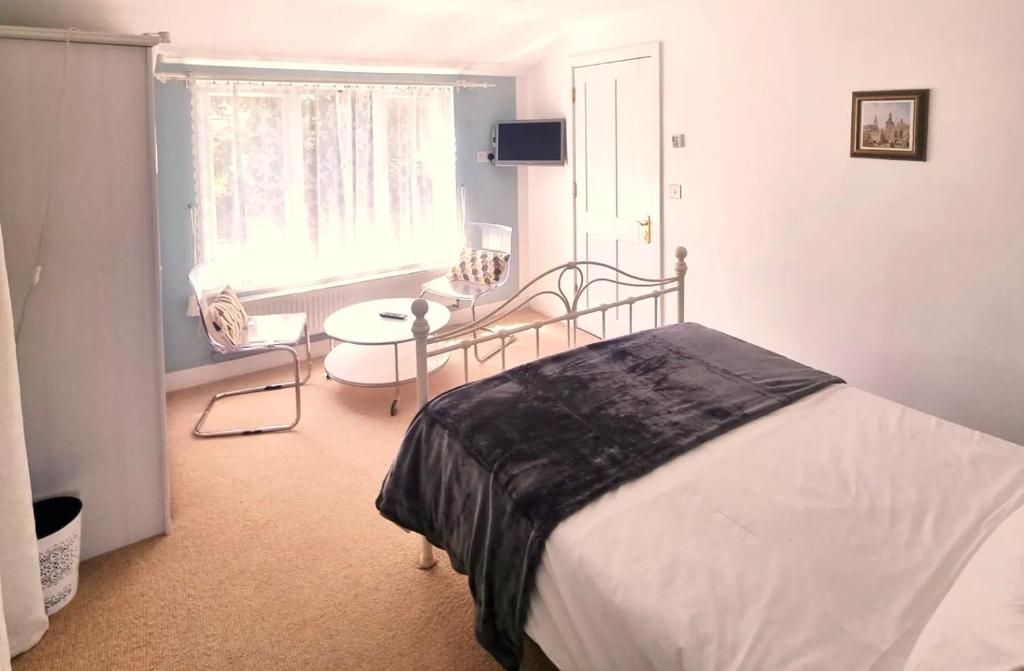 布罗肯赫斯特Oak Tree Rooms LTD的一间卧室配有一张床、一张桌子和一个窗户。
