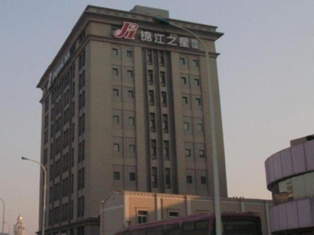 天津Jinjiang Inn Tianjin Station Jinwan Square的一座高大的建筑,上面有标志