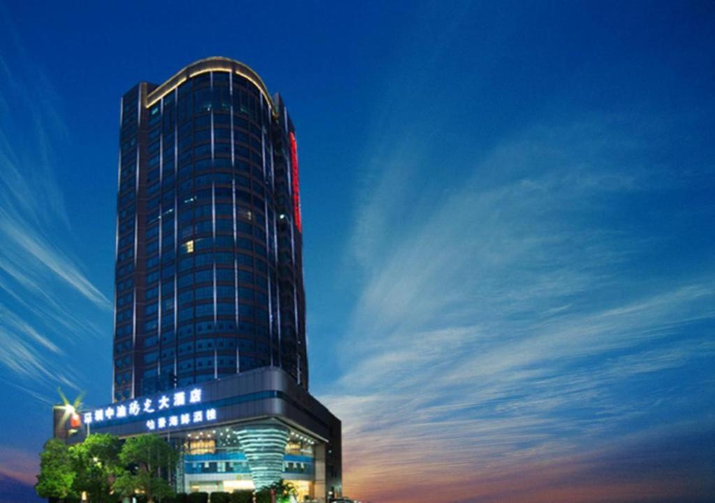 深圳Grand Soluxe Zhongyou Hotel Shenzhen的一座高大的建筑,晚上有标志