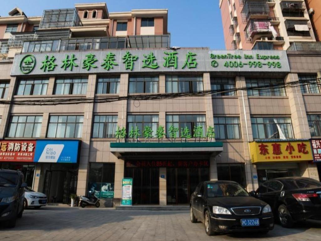 共青城GreenTree Inn Express Gongqing City Nanchang University的前面有汽车停放的建筑