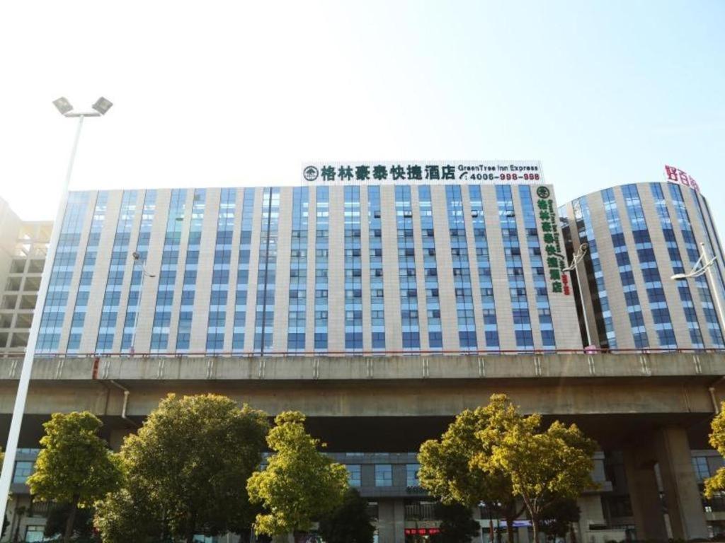 苏州GreenTree Inn Suzhou Railway Station North Square Haobainian Wedding Dress City Express Hotel的大楼顶层的一栋带蓝色窗户的大型建筑