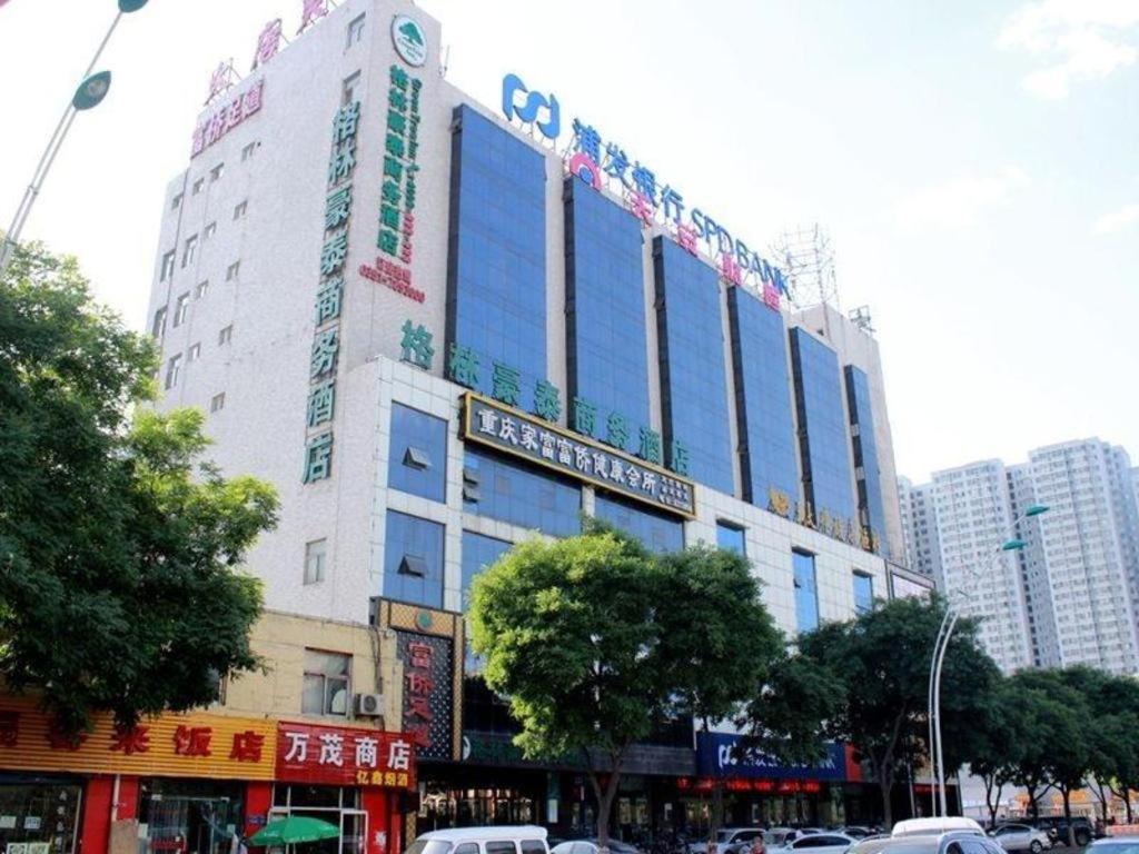 太原GreenTree Inn Taiyuan PinGYAng Road Business Hotel的一座高大的白色建筑,上面有很多标志