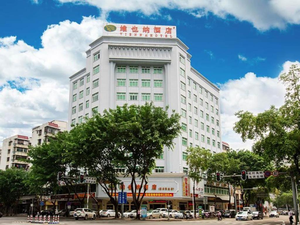 惠州Vienna Hotel Huizhou West Lake Maidi South Road的一座白色的大建筑,上面有标志