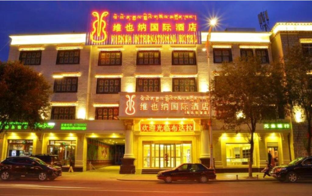 拉萨Vienna International Hotel Lhasa Potala Palace的前面有 ⁇ 虹灯标志的大建筑