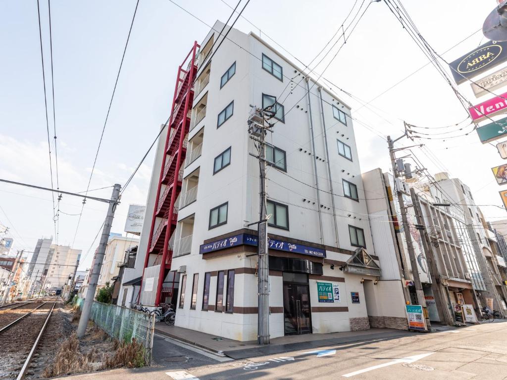 高松Tabist City Hotel Patio的一条城市街道上高大的白色建筑