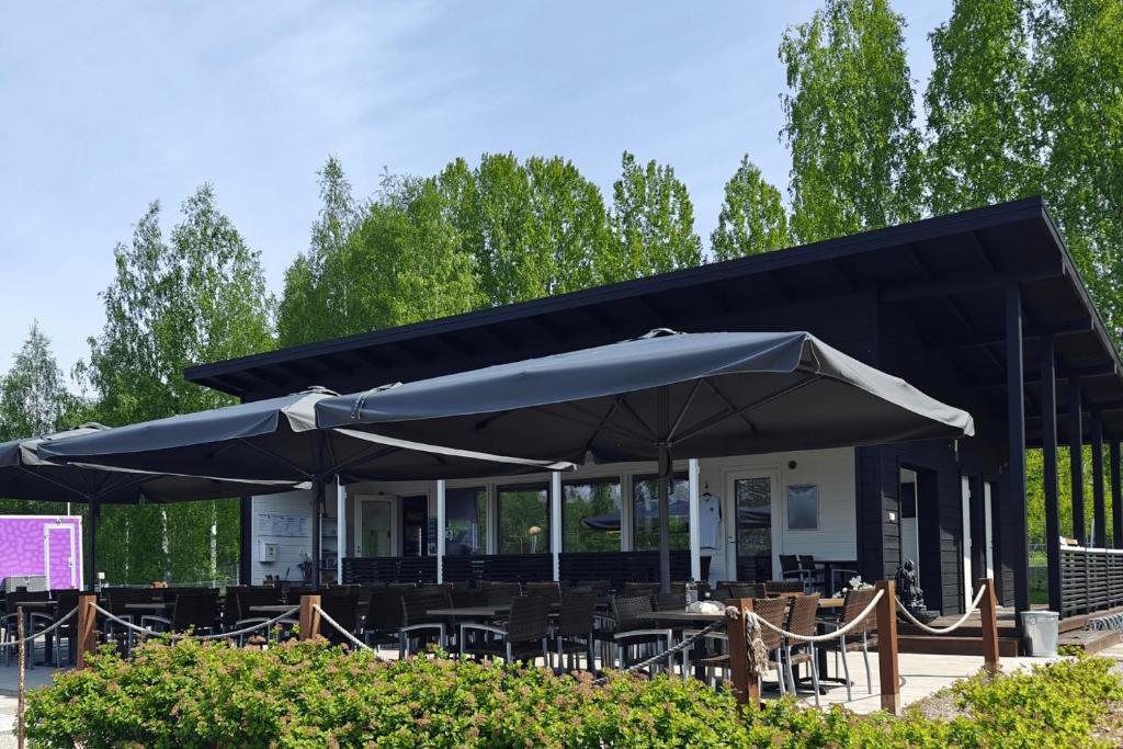 萨翁林纳Vuohimäki Camping Savonlinna的一间设有桌子和遮阳伞的黑色餐厅
