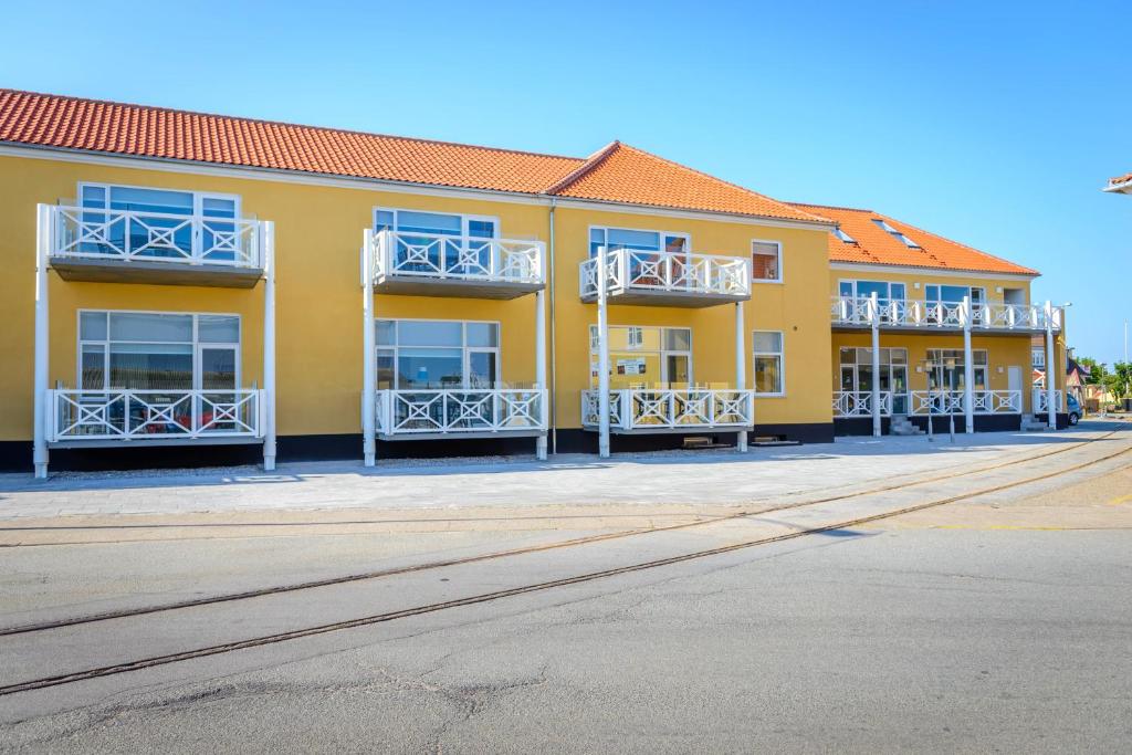 斯卡恩Skagen Havn Lejligheder的黄色的建筑,街道上设有白色的阳台