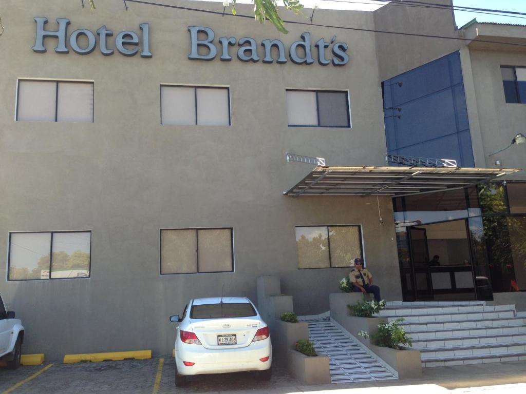 马那瓜Hotel Brandts Ejecutivo Los Robles的停在酒店品牌大楼前的白色汽车