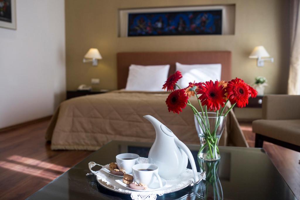 塞萨洛尼基戴维酒店的一间设有床铺和一张带花瓶的桌子的房间