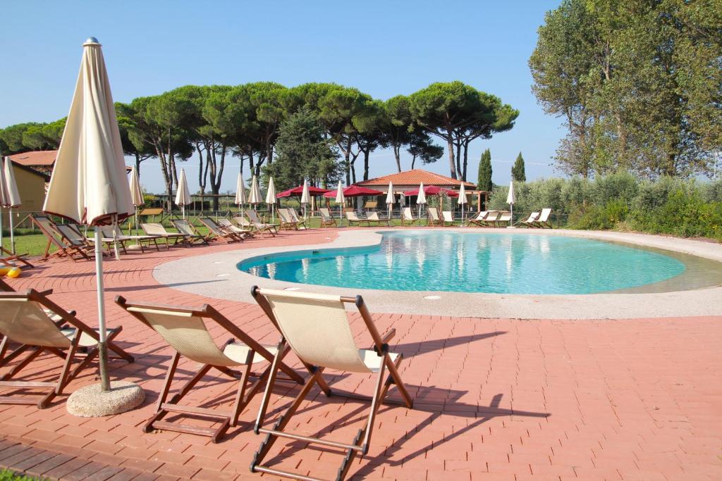 蒂勒尼亚蒂勒尼亚公寓式酒店的一组椅子和一个带遮阳伞的游泳池