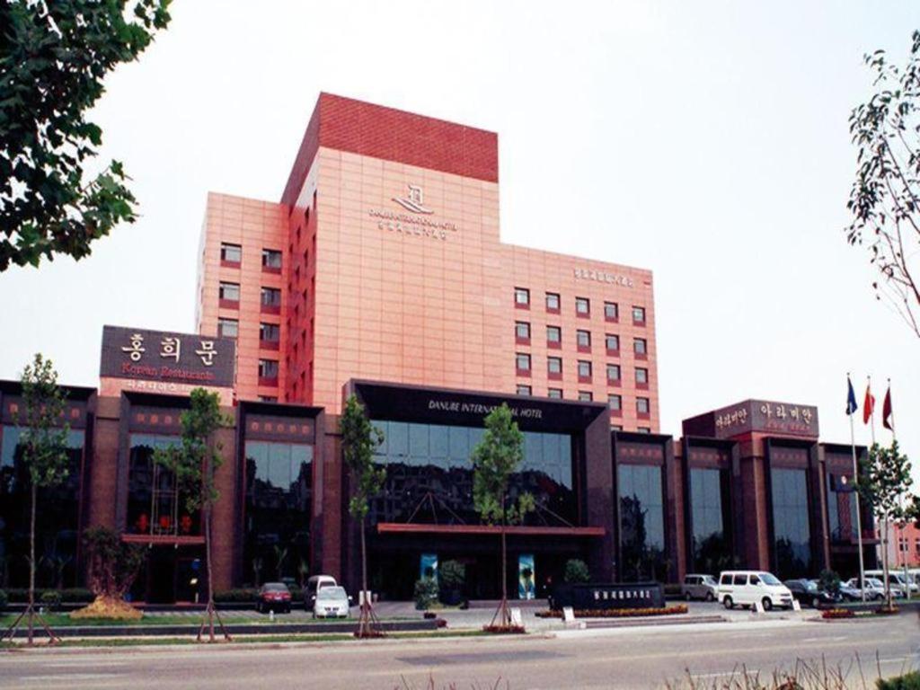 青岛Qingdao Danube International Hotel的一座大型建筑,前面有汽车停放