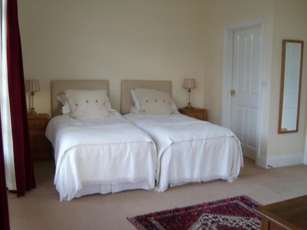 Tilbrook霍尔农场住宿加早餐旅馆的一间卧室配有两张带白色床单和镜子的床