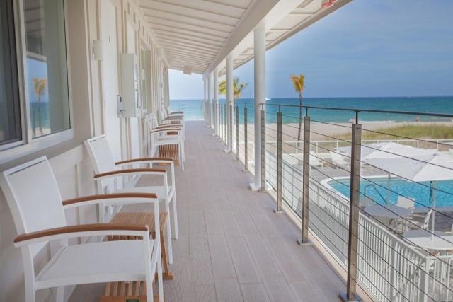 劳德代尔堡潮汐酒店的一个带白色椅子的阳台和一个游泳池