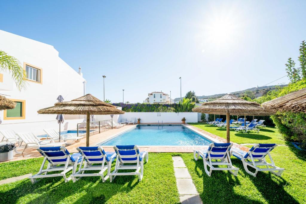 卢斯绿洲海滩公寓酒店的别墅设有一个游泳池、草坪椅和遮阳伞
