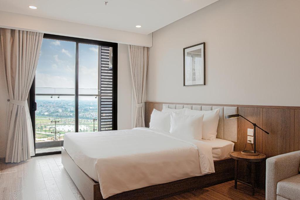 海阳Mandala Hotel & Suites Hai Duong的一间卧室设有一张大床和一个大窗户