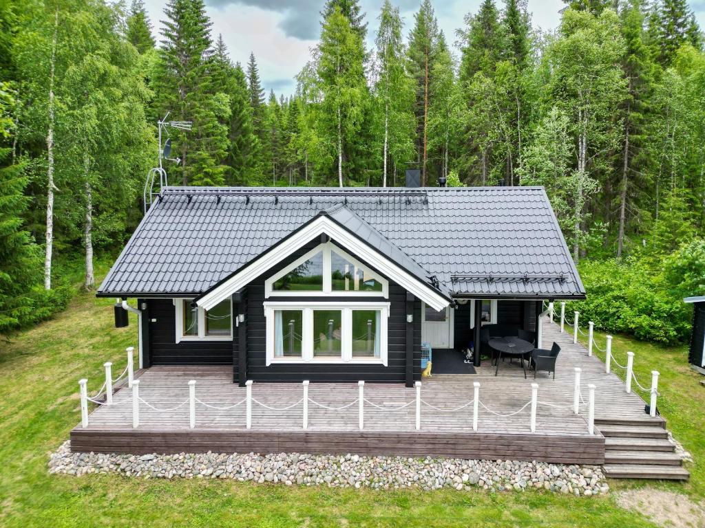 PuolankaLähderinne - Beachfront 2 bedroom log cabin, private beach & sauna的树林中带大甲板的小房子