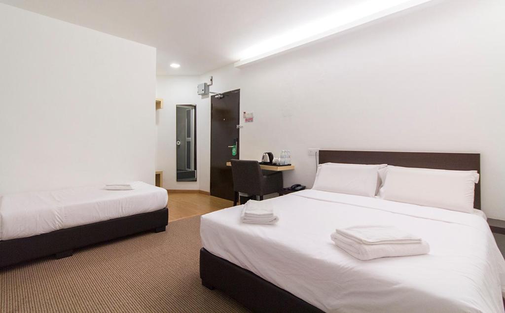 劳勿HOTEL RAUB since 1968的一间卧室配有两张带白色床单的床和一张书桌