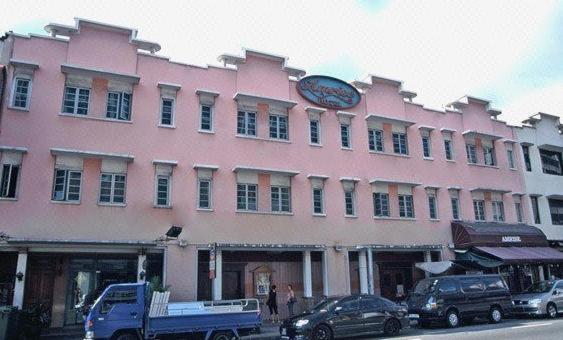 新加坡Amrise Hotel的粉红色的建筑,上面有时钟