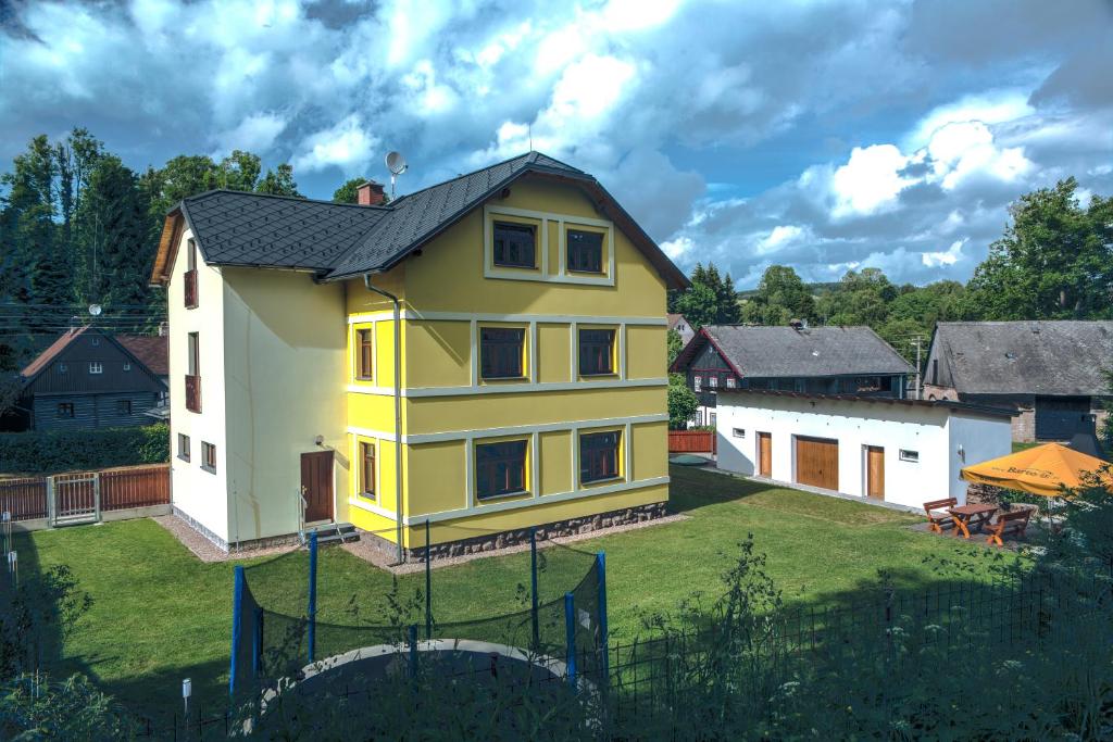 Bartošovice v Orlických HoráchApartmány Barto21的院子里有黑色屋顶的黄色房子