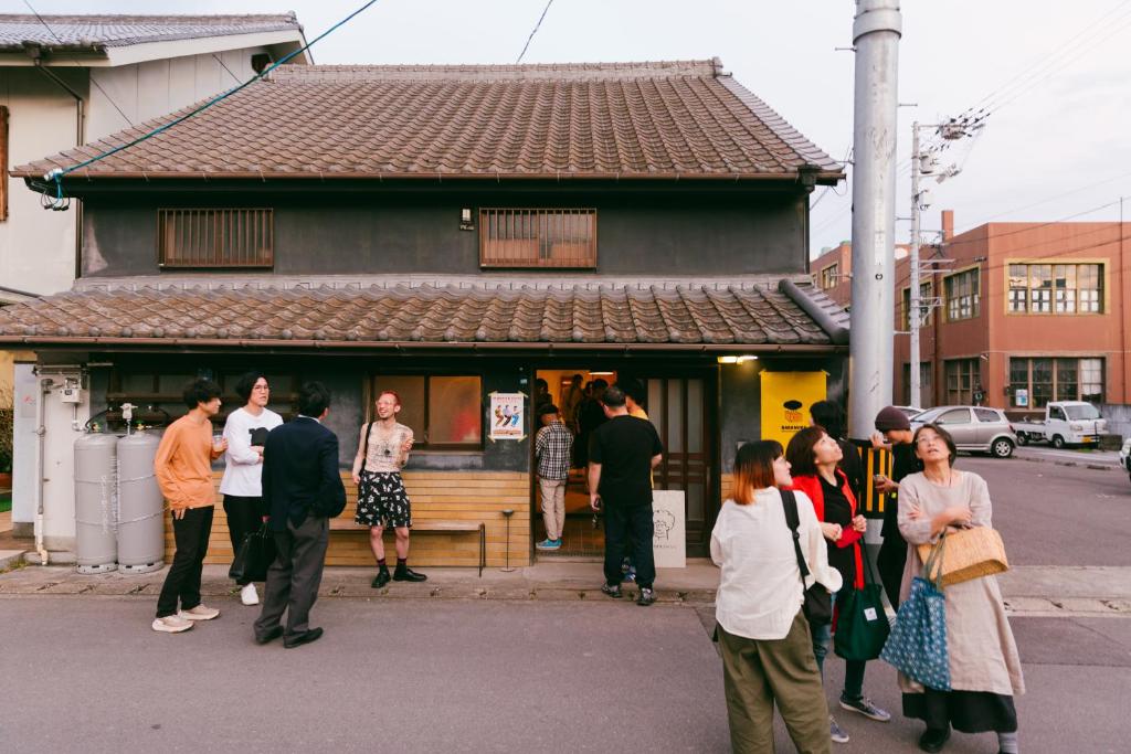 丸龟市丸亀ゲストハウスババノバ的一群人站在建筑物外