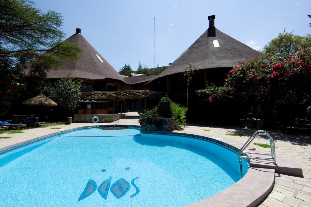 Ololaimutiek马赛马拉索帕山林小屋的一个带茅草屋顶房屋的游泳池