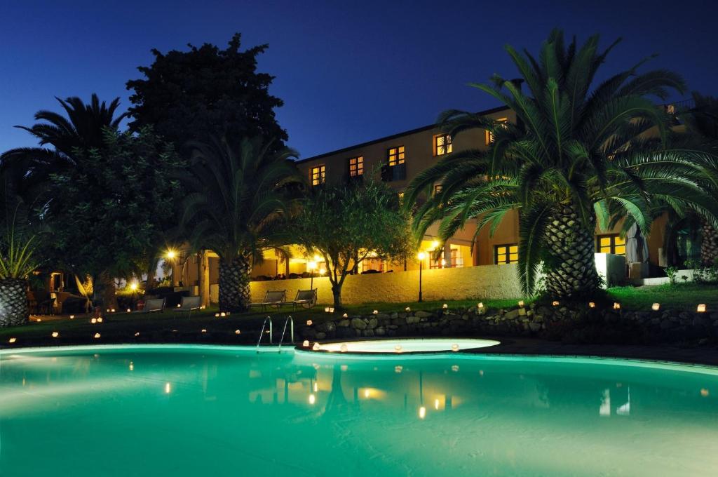 阿尔盖罗Alghero Resort Country Hotel & Spa的一座游泳池,在晚上在建筑物前